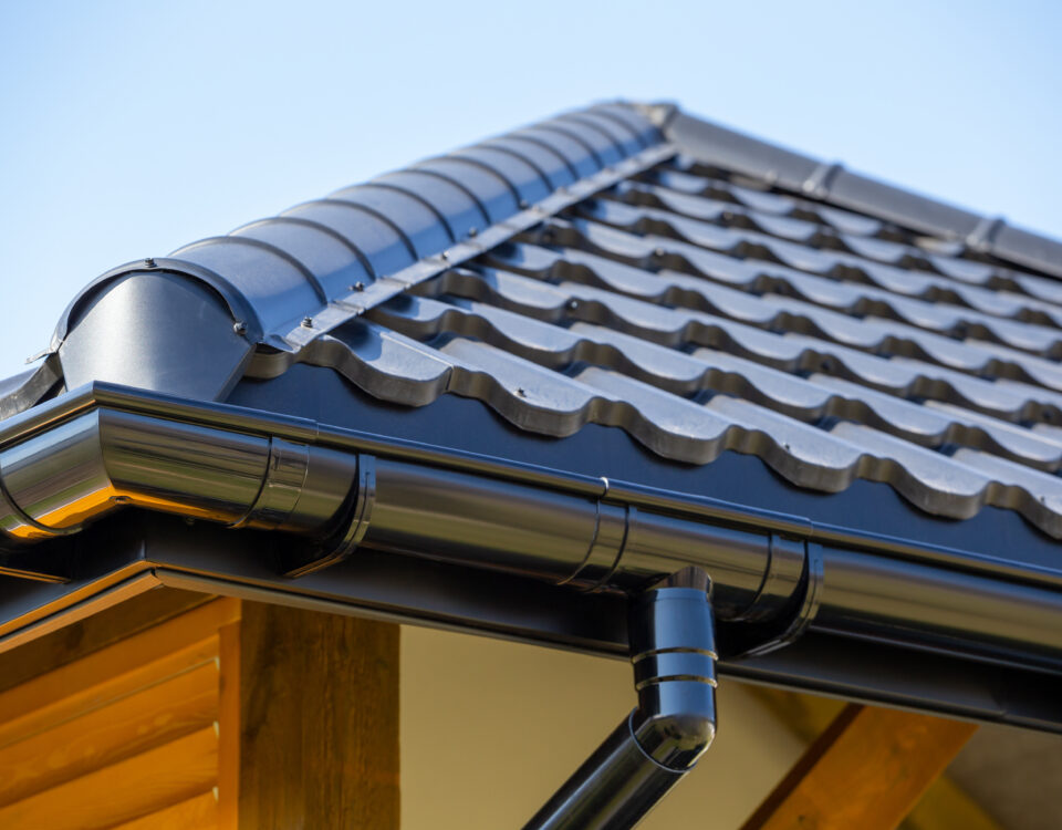 Corner of the new modern house with roof, gutter and wooden shutter under blue sky